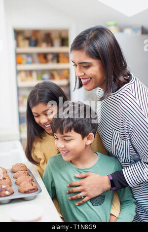 Mother and children baking muffins in kitchen Stock Photo
