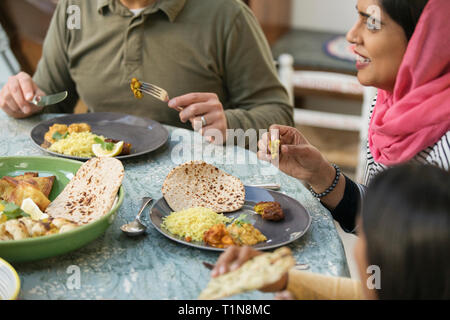 Woman in hijab eating dinner with family at table Stock Photo