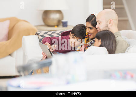 Family using digital tablet on living room sofa Stock Photo