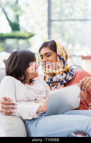 Happy mother in hijab using digital tablet with daughter Stock Photo