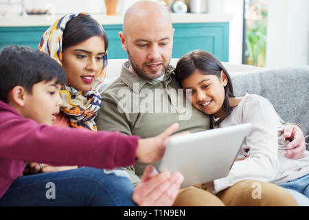 Family using digital tablet on sofa Stock Photo