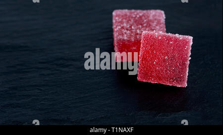 wo pieces of red marmalade lies on a stone black background Stock Photo