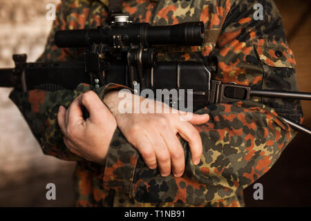 The soldier is holding the gun in his hands Stock Photo