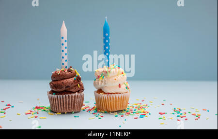 Birthday cupcakes on blue pastel background. Two cupcakes vanilla and chocolate with blue candles, copy space. Stock Photo