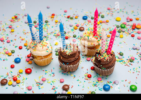 Birthday cupcakes on blue pastel background. Four cupcakes vanilla and chocolate with blue and pink candles Stock Photo