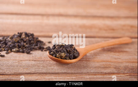 Black dry tea leaves with wooden spoon on the wooden background Stock Photo