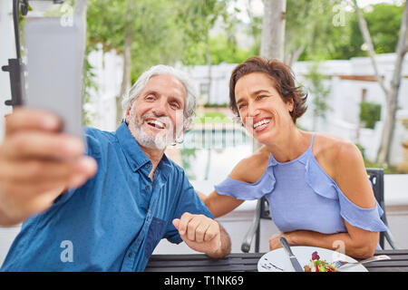 Mature couple taking selfie with camera phone on hotel patio Stock Photo