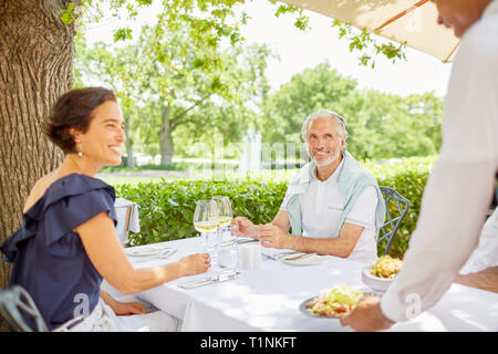 Waiter serving food to mature couple dining at patio table Stock Photo