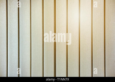 The yellow glow of the sun through the closed vertical blinds on the windows Stock Photo