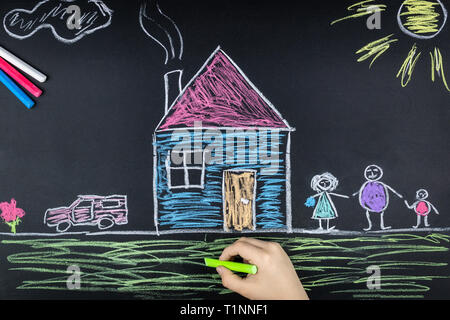 child draws a family a house and a car on the school Board Stock Photo