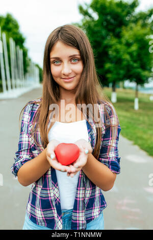 Happy girl teenager 13-16 years. Holds toy heart hands. Concept gift for Valentine's day, love joy. Donation blood transfusion, organ transplantation Stock Photo