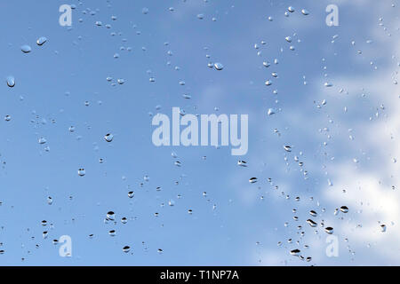 Sky view through window with rain drops on blue blurred backgroud. - Image Stock Photo