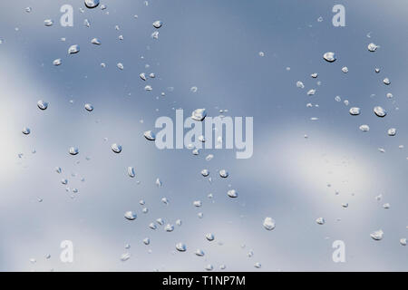 Sky view through window with rain drops on blue blurred backgroud. - Image Stock Photo