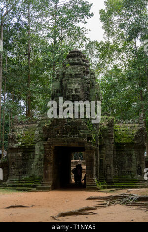 Tourists going through an ancient Angkor gate near Angkor Wat Stock Photo
