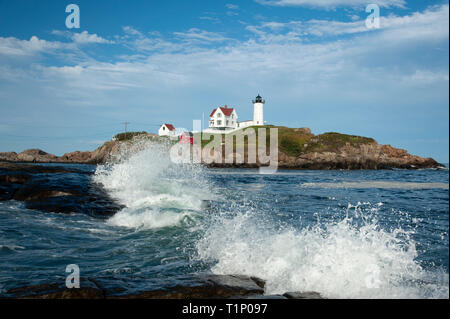 Waves break during high tide in front of Nubble (Cape Neddick) lighthouse on a warm summer day in Maine. Stock Photo