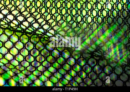 Wavy netting. Light rays artistic detail. Abstract mesh texture. Green lightbeams glowing through black hexagonal cells. Shiny grid pattern background. Stock Photo