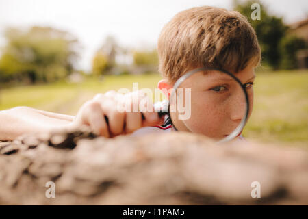 Boy looking through magnifying glass on a sunny day. Boy exploring with magnifying glass. Stock Photo
