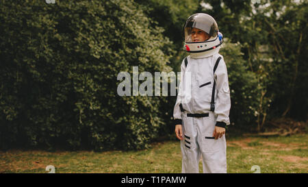 Boy wearing white armor and helmet standing outdoors. Cute boy in space suit and helmet playing astronaut in playground. Stock Photo