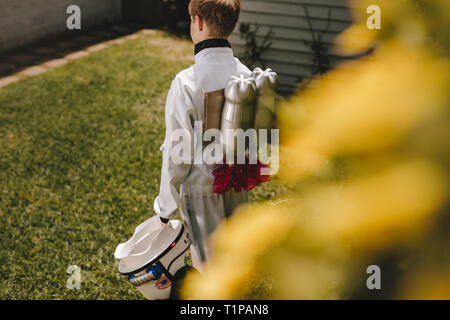 Rear view of boy in space suit carrying a toy jetpack on his back. Boy pretending to be an astronaut playing in backyard. Stock Photo