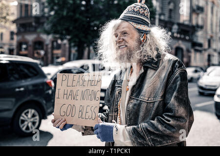 Long-haired desperate senior homeless wearing ragged clothes Stock Photo