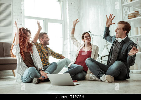 Delighted positive people giving each other high five Stock Photo