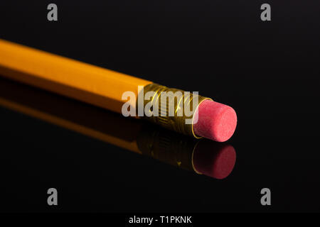 One whole yellow pencil cup eraser isolated on black glass Stock Photo