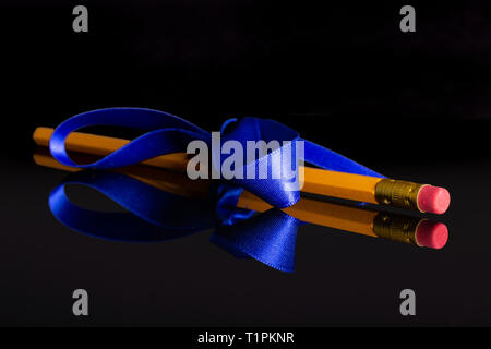 One whole yellow pencil tied by ribbon isolated on black glass Stock Photo