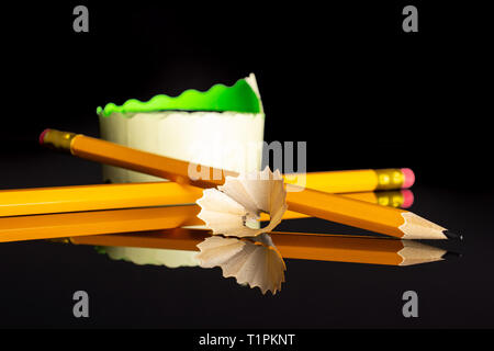 Group of two whole yellow pencil fan-shaped shaving with a sticker roll isolated on black glass Stock Photo