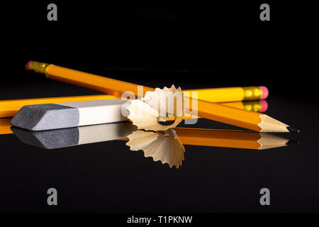 Group of two whole yellow pencil fan-shaped shaving with an eraser isolated on black glass Stock Photo