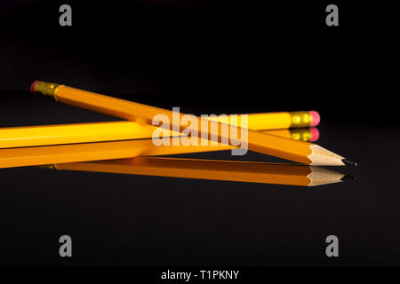 Group of two whole yellow pencil isolated on black glass Stock Photo