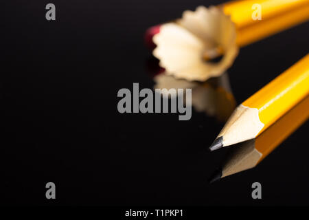 Group of two whole yellow pencil fan-shaped shaving isolated on black glass Stock Photo