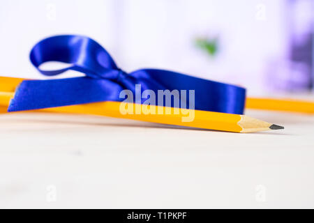 Group of two whole yellow pencil tied by ribbon with red flowers on white in background Stock Photo