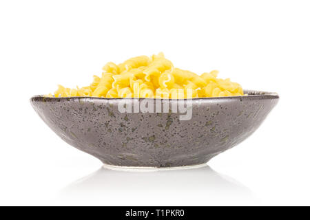 Lot of pieces of raw italitan yellow pasta torti in a grey ceramic bowl isolated on white background Stock Photo