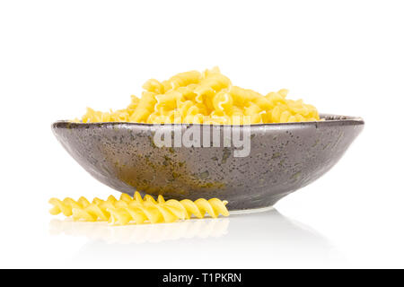Lot of pieces of raw italitan yellow pasta torti in a grey ceramic bowl isolated on white background Stock Photo