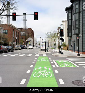 Protected bike lane and intersection markings on city street. Bicycle traffic lights and signage painted on green and white Stock Photo