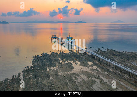 aerial view beautiful sunrise at golden Buddha standing statue on pavillion in the sea beside Phayam temple pier. Phayam temple is a landmark of Phaya Stock Photo