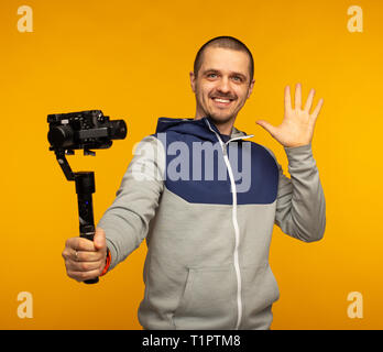 Man vlogger or video blogger holding camera on gimbal and smiling in camera Stock Photo