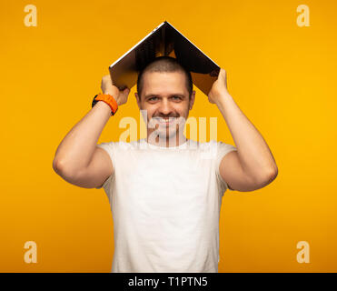 Man freelancer or IT programmer holding laptop over his head Stock Photo