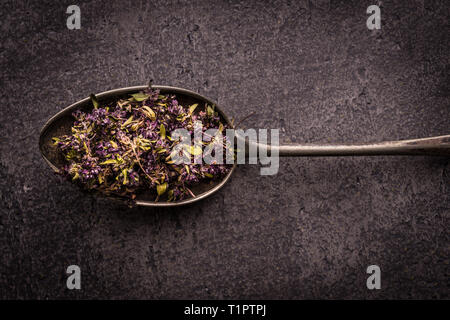 Dry Tea Leafs in Rustic Spoon on Dark Stone Background Stock Photo