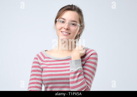 Smiling young caucasian woman in striped clothes and glasses. She is looking confident at camera Stock Photo