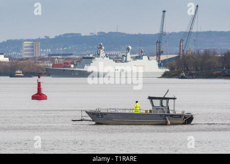 Glasgow, Scotland, UK. 28th Mar, 2019. Exercise Joint Warrior preparations on the River Clyde, Glasgow. The tiny Renfrew Ferry - a passenger ferry service linking the north and south banks of the River Clyde in Glasgow - makes a crossing after the giant Danish HDMS Absalon L16 passes by ahead of her participation alongside warships, submarines and aircraft from 13 other countries for the two-week exercise in Scotland between March 30 and April 11 Credit: Kay Roxby/Alamy Live News Stock Photo