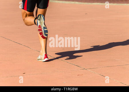 Photo behind legs of athlete running through stadium Stock Photo - Alamy