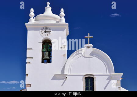 Top of a white washed bright medieval church with bell tower contrasting to blue sky at a sunny day Stock Photo