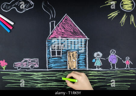 child draws a family a house and a car on the school Board Stock Photo