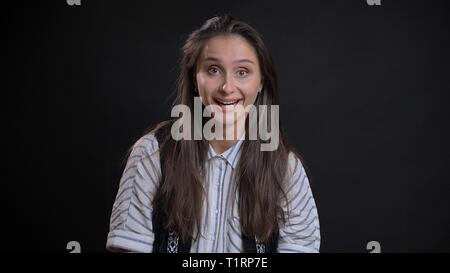 Closeup portrait of young cute caucasian female with brunette hair getting excited and smiling happily while looking straight at camera with isolated Stock Photo