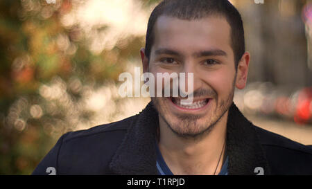 Portrait of caucasian man smiling happily into camera on street background. Stock Photo