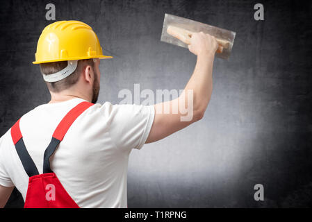 Rear view of a worker plastering a wall indoors Stock Photo