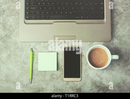Laptop computer ,mobile phone and coffee cup on work desk against Grunge background Stock Photo
