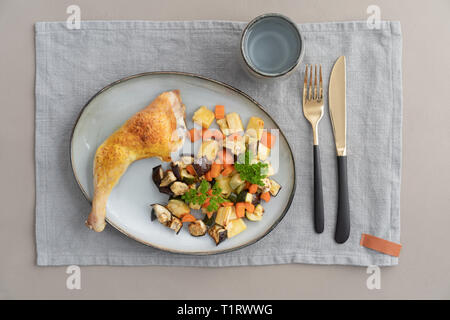 Place setting chicken dinner with oven roasted chicken leg and roasted vegetables Stock Photo