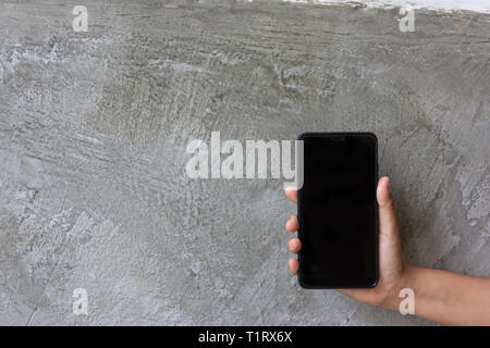 Asian woman hand hold moblie phone on grey cement background Stock Photo